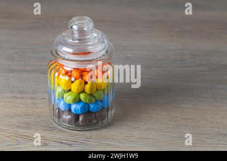 Milk chocolate Peanuts in a glass jar on a wooden table Stock Photo