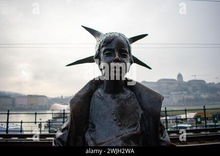 The original 50 cm statuette of the Little Princess Kiskirálylány Statue sitting on the railings of the Danube promenade in Budapest, Hungary Stock Photo