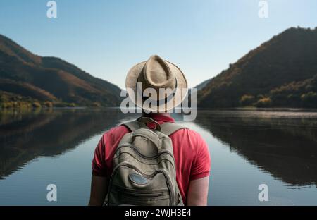 Traveler alone man  with backpack enjoy nature on river valley and looking at amazing mountains - Wanderlust and adventure travel. Stock Photo