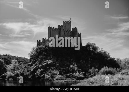 A black and white photo of Almourol castle and stream nestled amidst a forested landscape Stock Photo