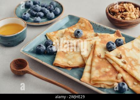 Thin pancakes, homemade crepes on a plate with blueberry, honey and nuts, closeup Stock Photo