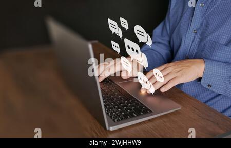Chat and stay connected via internet. A man uses computer laptop for online communication. Virtual speech bubbles or balloon icons while using social Stock Photo