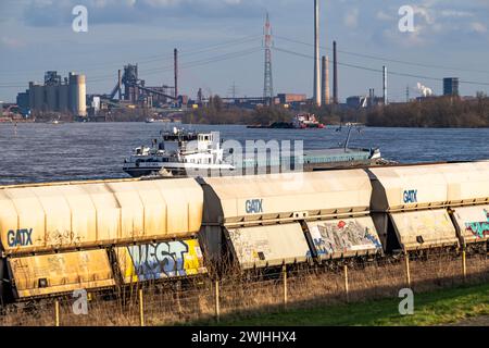 The Rhine near Duisburg, cargo ships, backdrop of the ThyssenKrupp Steel steelworks in Duisburg Marxloh, blast furnace Schwelgern 1, freight wagons in Stock Photo