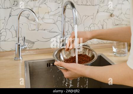 Closeup view of female hands rinsing rice under the tap Stock Photo