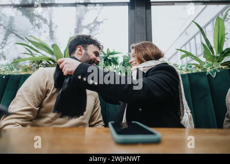 Two young entrepreneurs share a light-hearted moment during a business meeting at a cozy urban coffee shop, displaying teamwork and camaraderie. Stock Photo