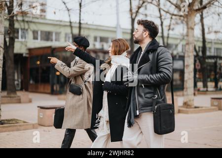Three young entrepreneurs are engaged in a vibrant discussion while walking through a city environment, highlighting remote work dynamics. Stock Photo