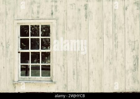The side of a white barn with a glass six pane window to the left. Stock Photo