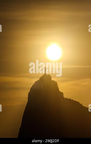 sun setting behind the statue of Christ the Redeemer in Rio de Janeiro, Brazil - October 16, 2023: sunset seen from the Urca neighborhood in Rio de Ja Stock Photo