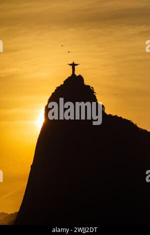 sun setting behind the statue of Christ the Redeemer in Rio de Janeiro, Brazil - October 16, 2023: sunset seen from the Urca neighborhood in Rio de Ja Stock Photo