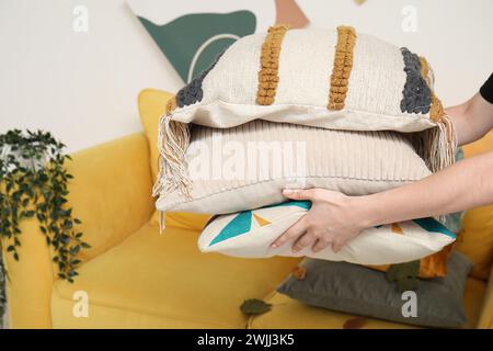 Woman putting stack of pillows on sofa Stock Photo