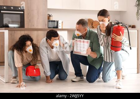 People with evacuation plan, first aid kit and fire extinguisher in burning kitchen Stock Photo