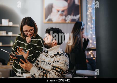 Two young business professionals engage in a collaborative work effort, using a tablet and taking notes in a warmly-lit cafe during the evening. Stock Photo