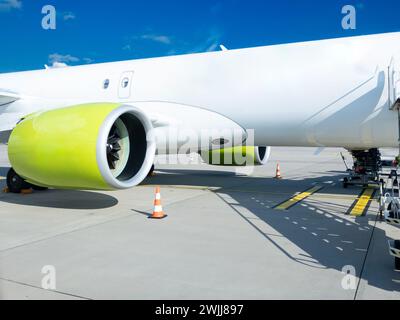 On the tarmac of a bustling European airport, a sleek cargo plane awaits its next voyage. The aircraft's large, strikingly colored engine hints at the Stock Photo