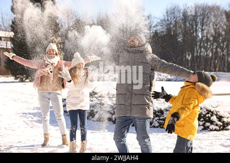 Happy family playing with snow in sunny winter park Stock Photo