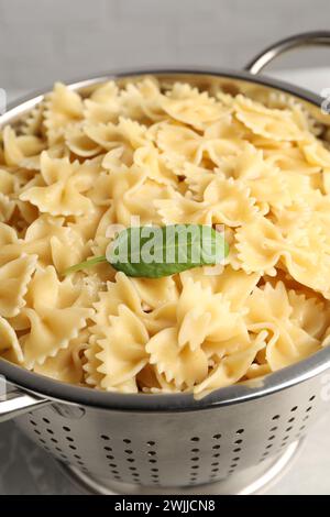 Cooked pasta in metal colander on grey table, closeup Stock Photo