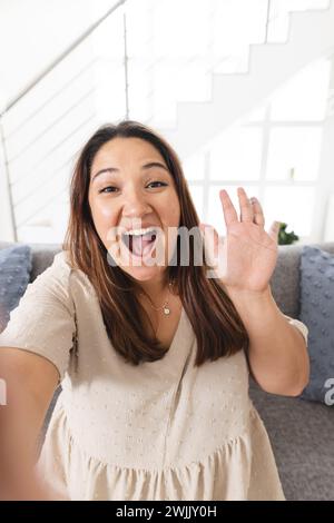 Young biracial woman takes a selfie at home on a video call, with copy space Stock Photo