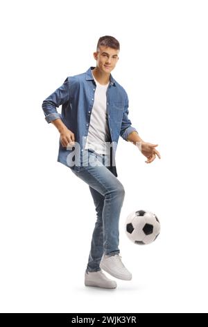 Casual young man kicking a football and looking at camera isolated on white background Stock Photo