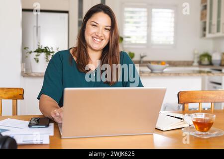 Young biracial woman works on her laptop at home Stock Photo