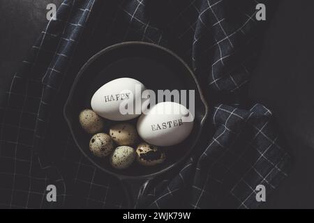 Quail eggs with Happy Easter stamped white eggs in stoneware pan on black background. Directly above table top shot. Stock Photo