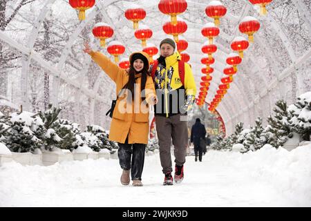 Happy toung couple walking on background of Chinese New Year decorations. Festive alley decorated with red paper lanterns in winter city Stock Photo