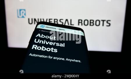 Cellphone with web page of Danish cobot company Universal Robots AS in front of business logo. Focus on top-left of phone display. Stock Photo