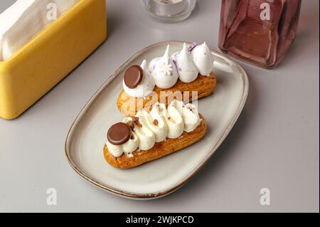 eclairs on a plate and coffee in a coffee shop on the table Stock Photo