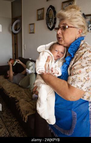 Grandmother holds her newborn grandson in her arms. Family weekend Stock Photo