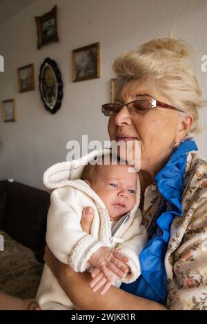 Grandmother holds her newborn grandson in her arms. Family weekend Stock Photo
