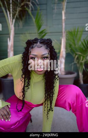 Model in neon outfit poses outside with colorful makeup Stock Photo