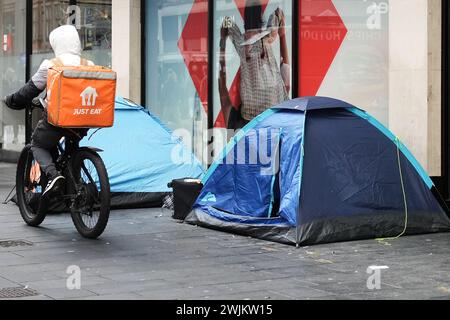 Rough sleeper tents inn Liverpool City Centre with a Just Eat rider passing by. Stock Photo