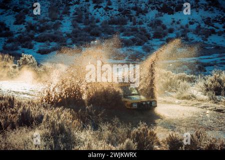 A backlit SUV drives through a puddle in the mountains. Stock Photo