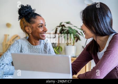 Side view of two females coworkers sitting at desk using digital tablet Stock Photo