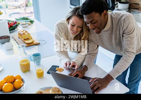 Adult woman holding credit card while boyfriend is using laptop Stock Photo