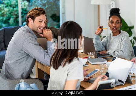 Coworkers gathered in office while working on laptops Stock Photo