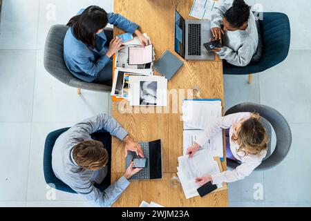 Advertising agency workers sitting at table using laptop Stock Photo
