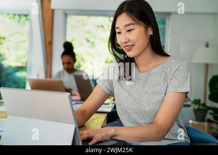 Female community manager using digital tablet while sitting at desk Stock Photo