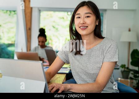 Female community manager using digital tablet while sitting at desk Stock Photo