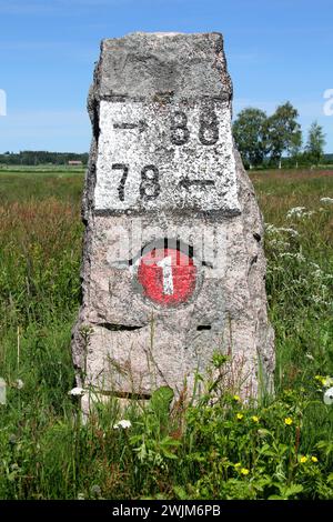 Old milestone made of granite by Highway 110 (Previously number 1) in Kitula, Finland with summer landscape. Stock Photo
