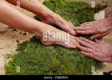 A mans hand massages a womans feet using thumb, fingers, and gentle gestures on the grass, providing a soothing and relaxing experience Stock Photo