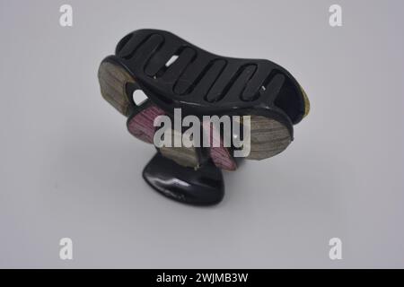 Women's accessories and things, black with purple inserts plastic hair crab arranged on white plastic background. Stock Photo