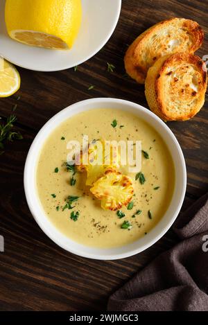 Cauliflower cheese soup in bowl over wooden background. Vegetarian or healthy diet food concept. Top view, flat lay Stock Photo