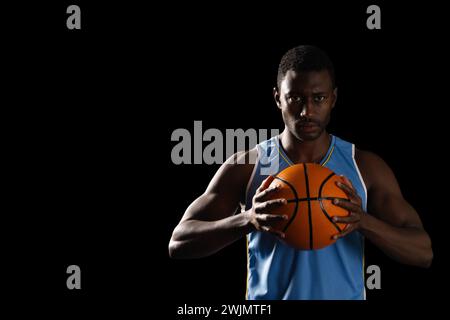 African American man holding a basketball on a black background, with copy space Stock Photo