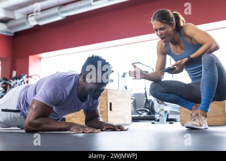 Fit young Caucasian woman coaches a fit African American man at the gym Stock Photo