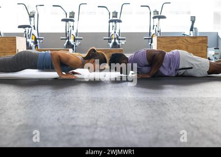 Fit young Caucasian woman and African American man doing planks at the gym Stock Photo