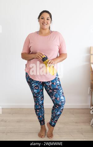 Young plus size biracial woman holding a water bottle at home Stock Photo