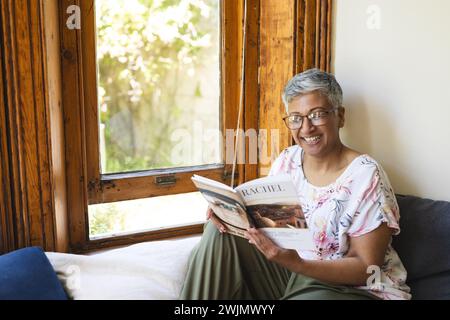 A mature biracial woman reading a magazine at home, with copy space Stock Photo