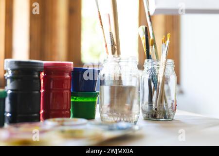 A variety of paintbrushes rest in a jar on an artist's table Stock Photo