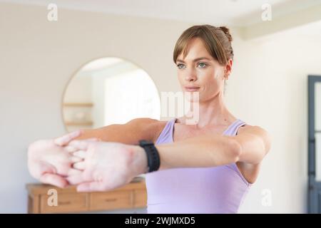 A young Caucasian woman is stretching her arms before a workout, with copy space Stock Photo