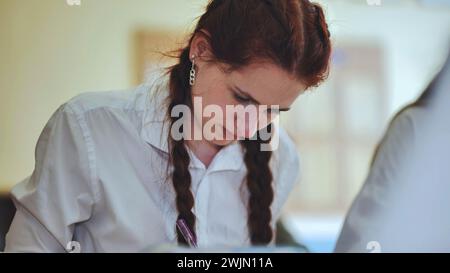 A girl student writes math formulas in a notebook. Stock Photo