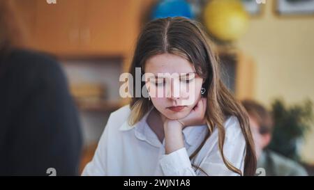 A girl student writes math formulas in a notebook. Stock Photo